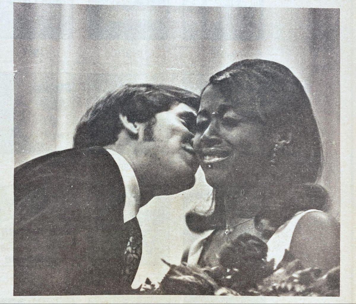 An old black-and-white photo from The Maneater Archive of Jill Young receiving roses while wearing a white dress and crying. Mike Eckman is kissing her on her cheek and wearing a suit.