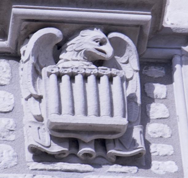 A close-up of a Memorial Union chiseled eagle holding a crest of the MU columns. 