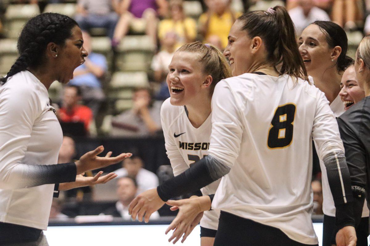 A Missouri volleyball player yells to her smiling teammates in celebration.