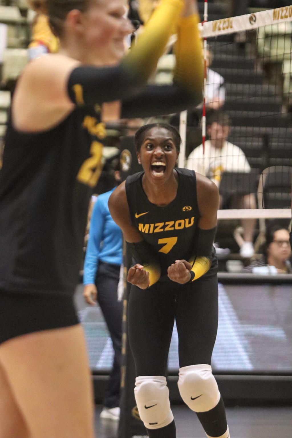 A Missouri volleyball player doubles over while yelling in celebration.