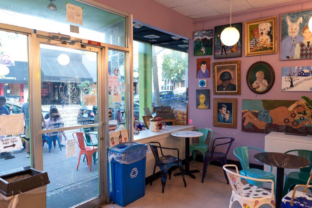 Inside view of Sparky’s with paintings on the wall, seating, and a view outside.
