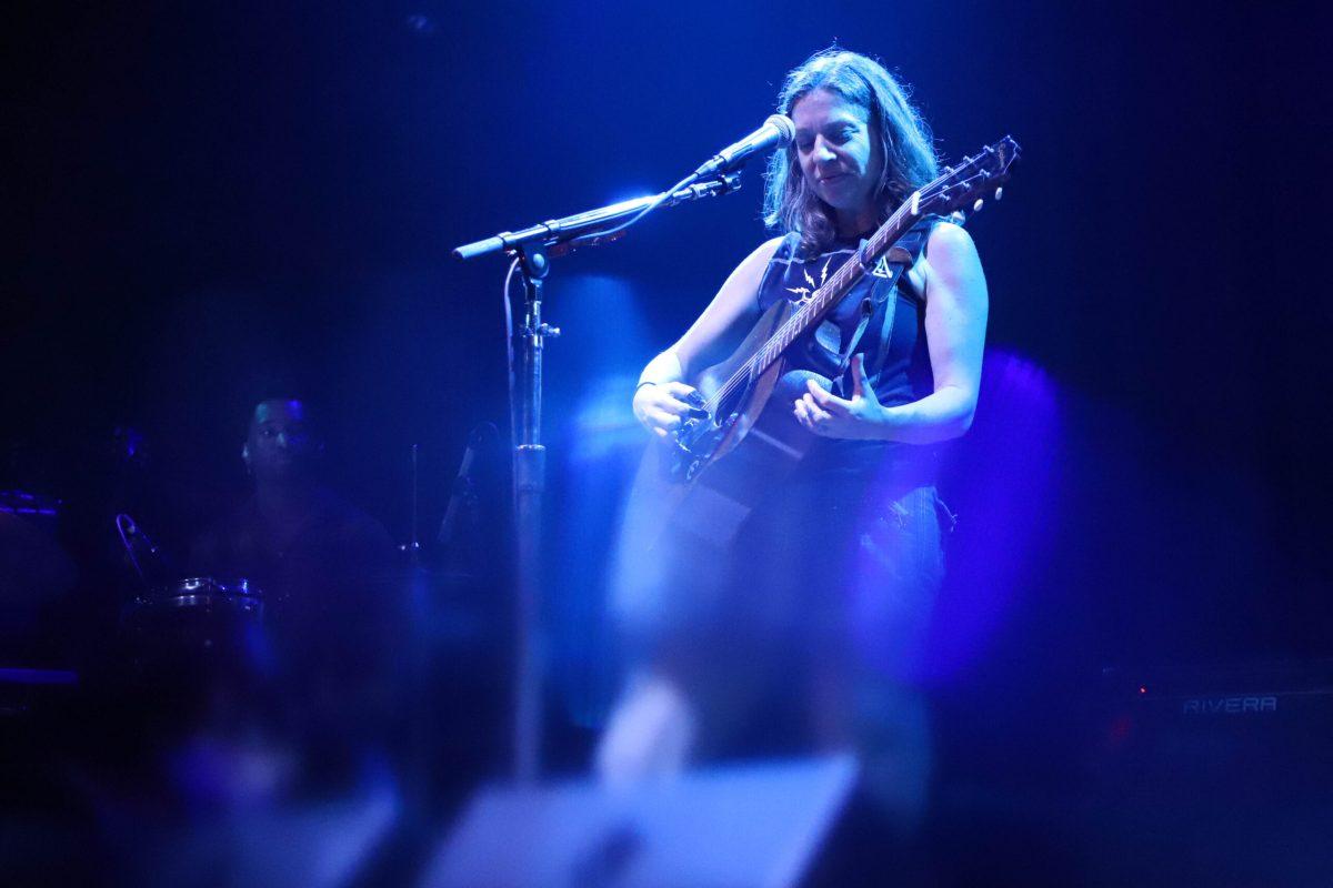 Musical performer playing guitar on stage.