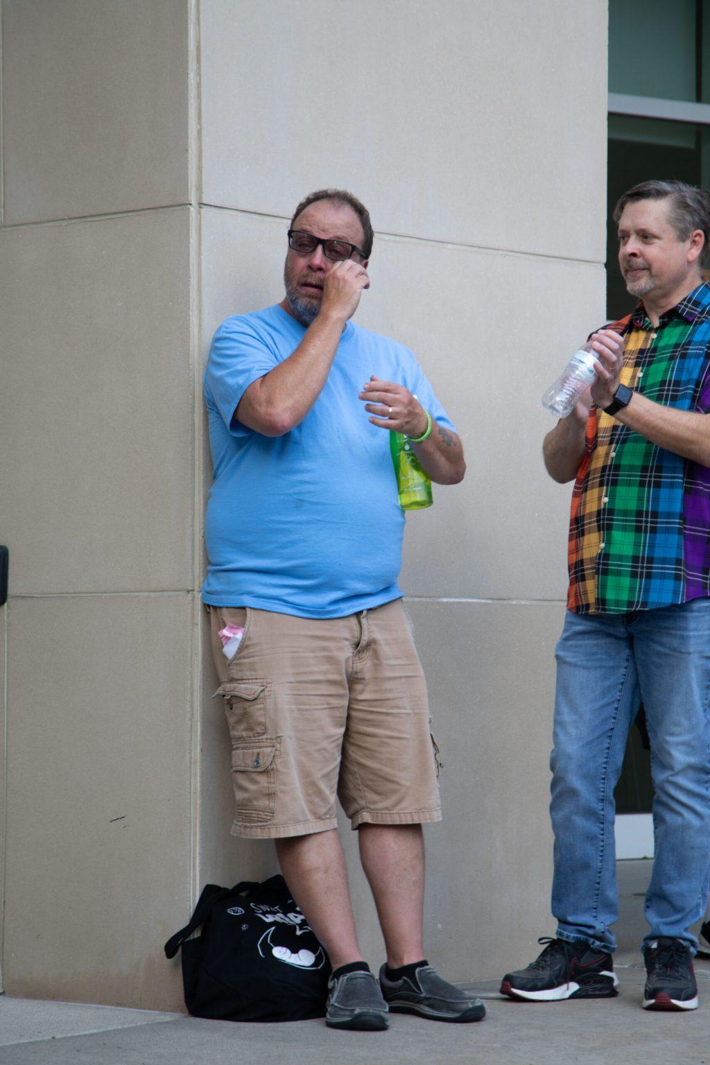Harry Castilow wipes away a tear with his right hand under his glasses.