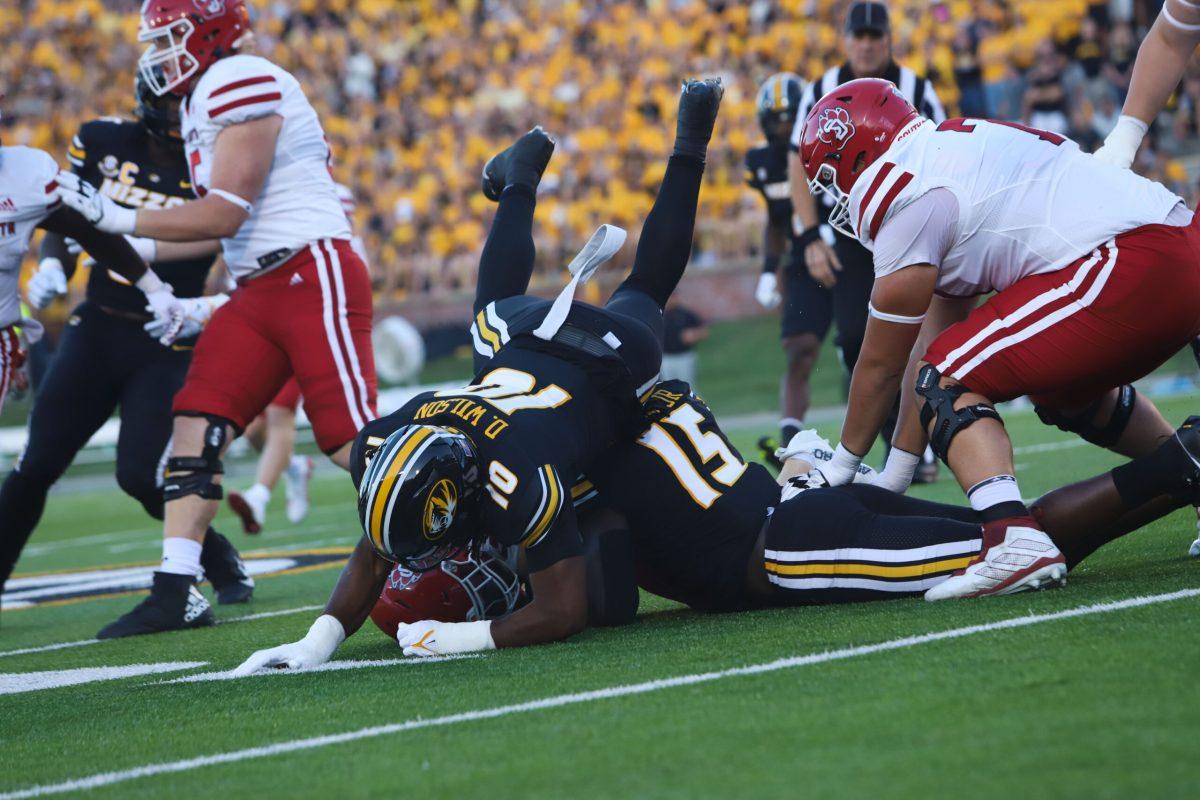 Two Missouri football players tackle a South Dakota player.
