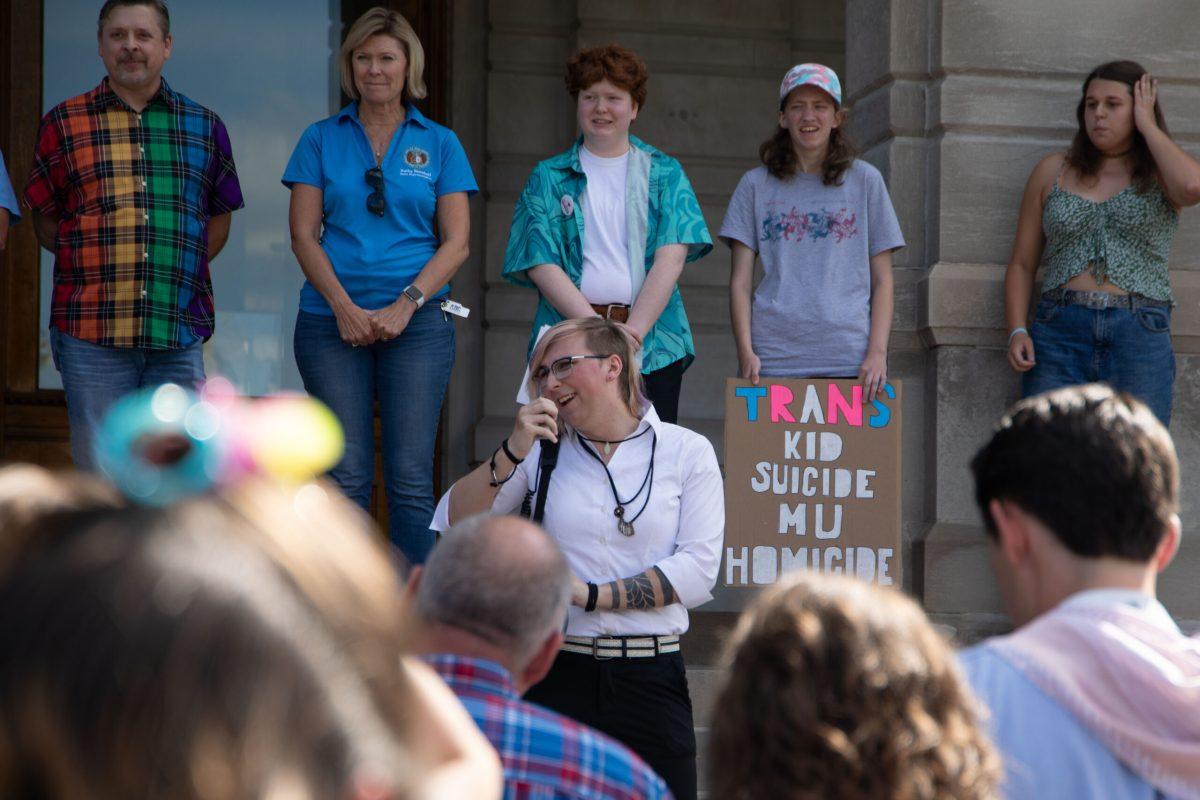 May Hall speaks into a megaphone on the steps of Jesse Hall while facing a crowd of supporters.