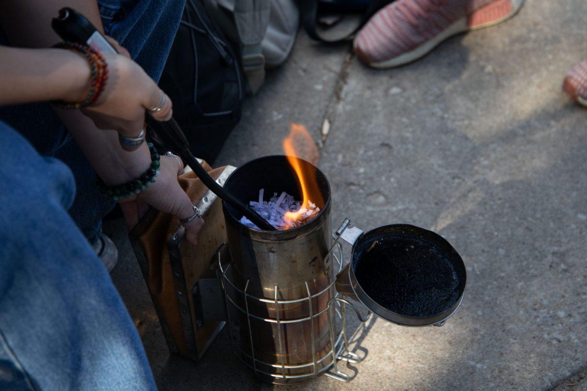 A person holds a lighter to the inside of the smoker to burn the paper.