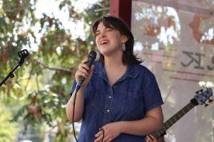 A woman stands and sings into a microphone.