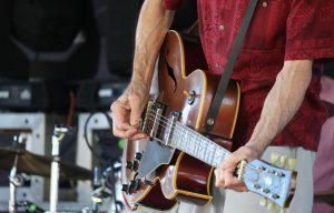 A hand strums a guitar.