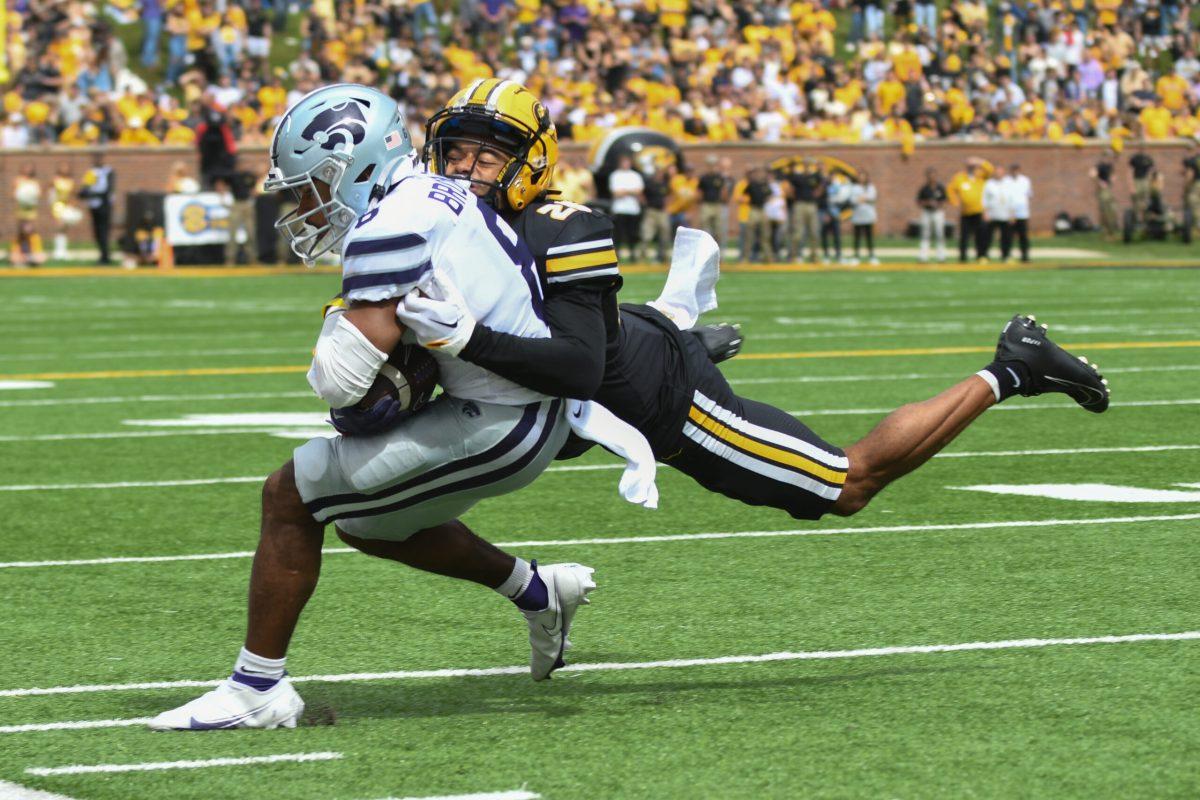 A Missouri football player jumps sideways to tackle a Kansas State football player.