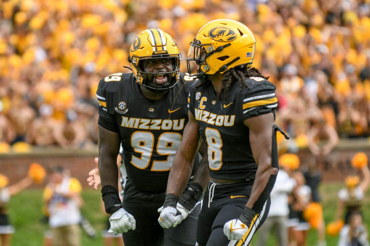 Two Missouri football players celebrate and yell at each other.