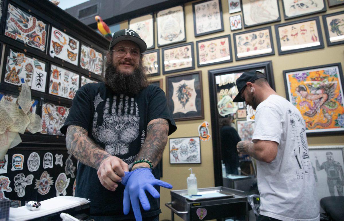 Sam Karstens puts on gloves before tattooing.