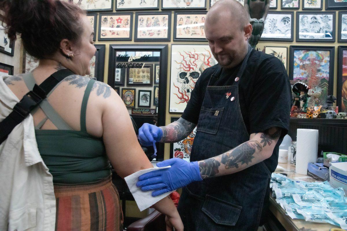 A customer smiles as Gabe Garcia preps her arm for the tattoo.