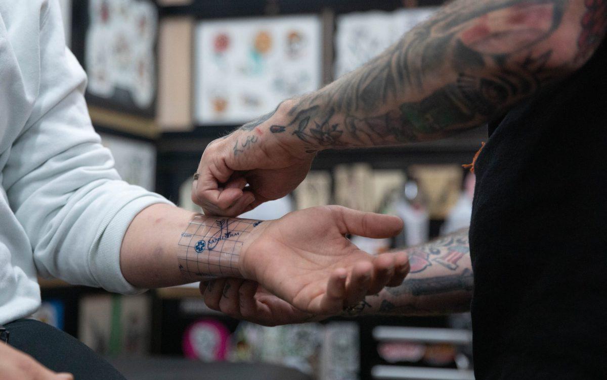 Colby Morton places a wrapping on client Jessica Hosack’s fresh tattoo.