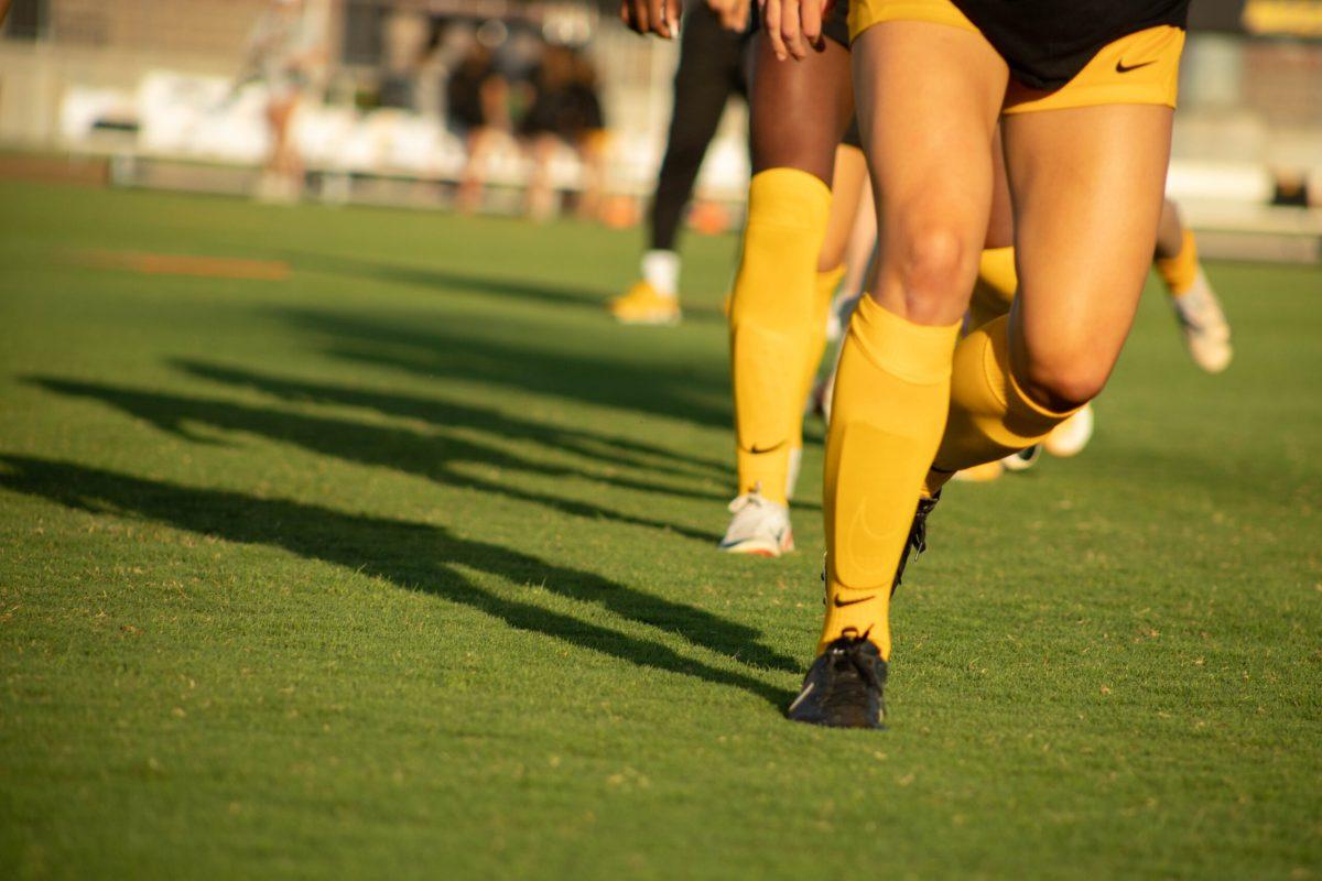 Soccer players’ legs striking the turf as they warm up.