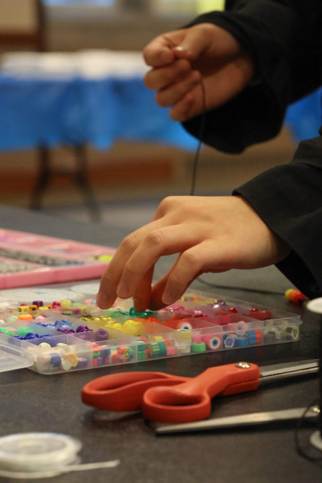 A student picking out a bead to make a bracelet.