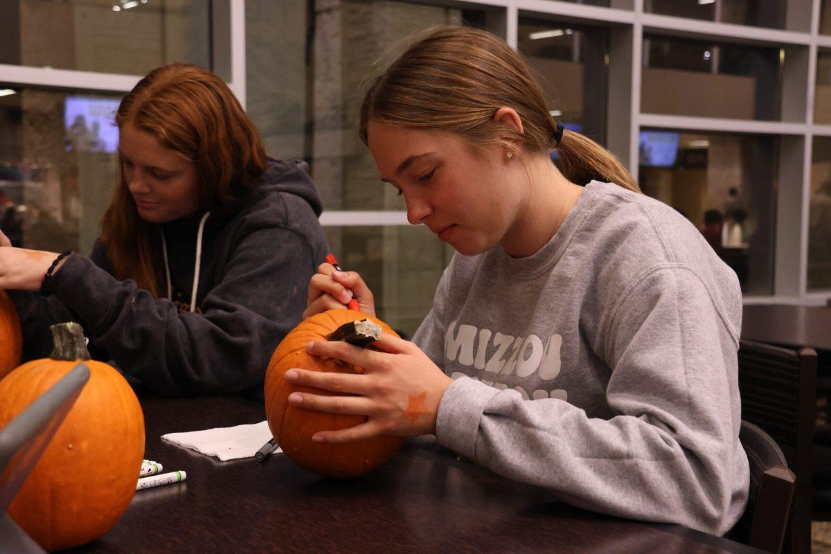 A student and her friends decorating their pumpkins.