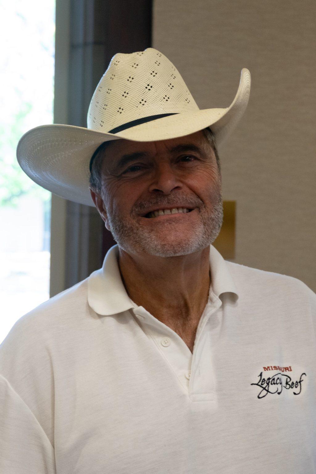 A man with a cowboy hat smiles.