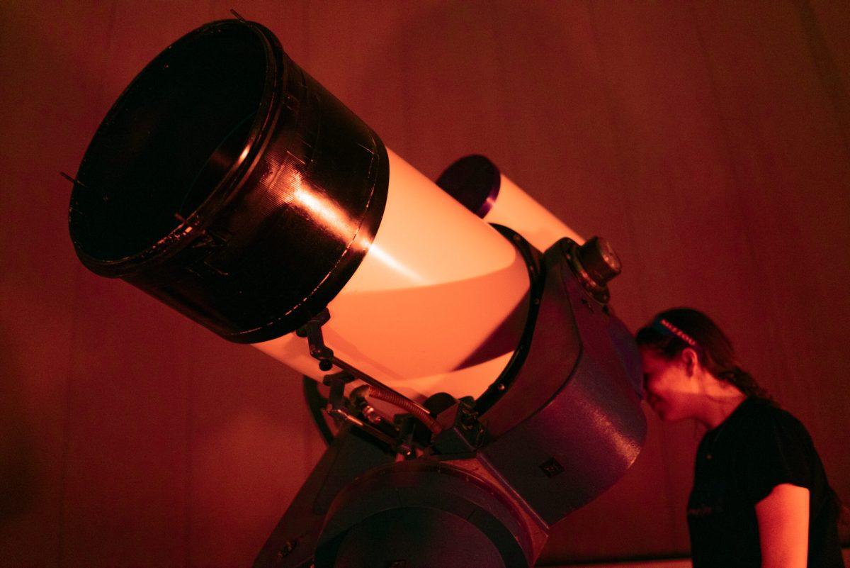Student looks into a telescope
