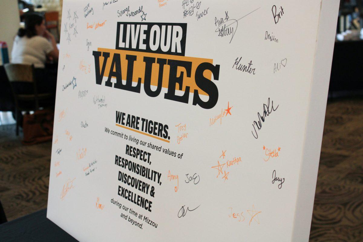 A white canvas propped on the table that has student signatures on it. The canvas reads, “Live our values. We are Tigers. We commit to living our shared values of Respect, Responsibility, Discovery, & excellence during our time at Mizzou and beyond.”