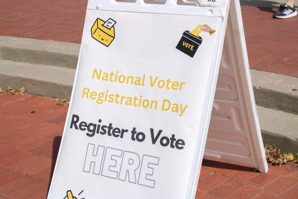 A foldable sign outside Speakers Circle which reads, “National Voter Registration Day. Register to Vote HERE.”