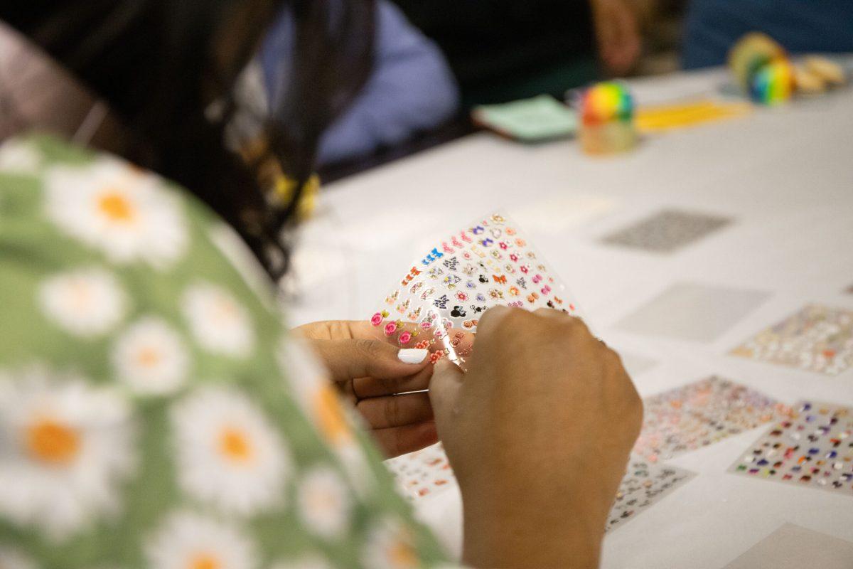  Sri Aishitha Koduru peels off small stickers from a clear plastic sheet for her nails.

