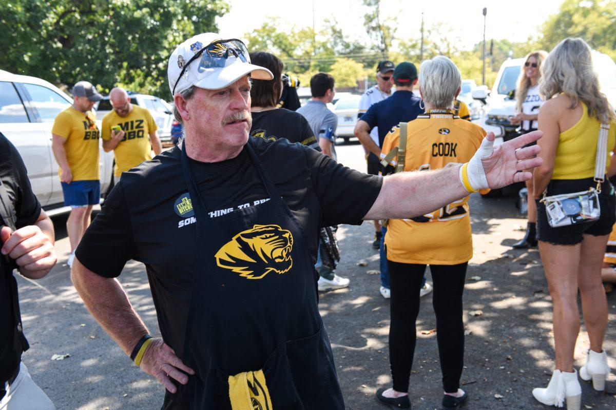 Older man gestures widely to his left
