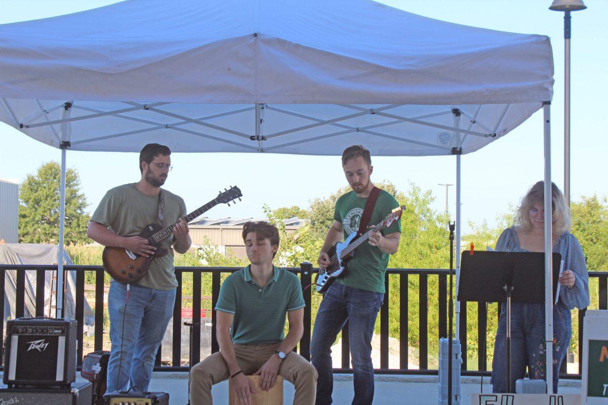Four band members perform under a tent.