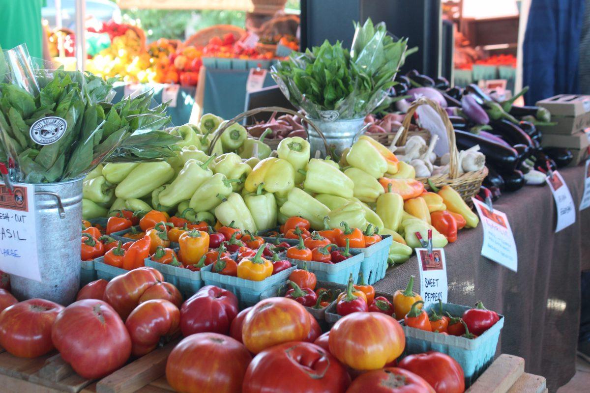 A colorful selection of produce including peppers and tomatoes sit out on a vendor’s table. 