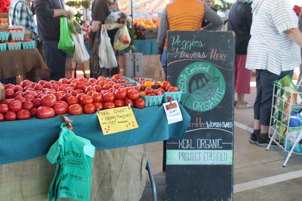 Tomatoes sit on a table next to a sign reading “USDA Organic Certified.”
