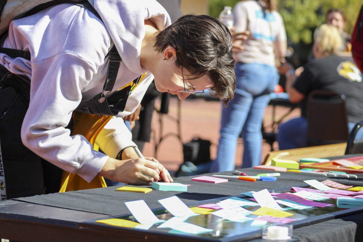 Junior Maggie Howell writes on a sticky note at Lowry Mall in Columbia, Missouri.
