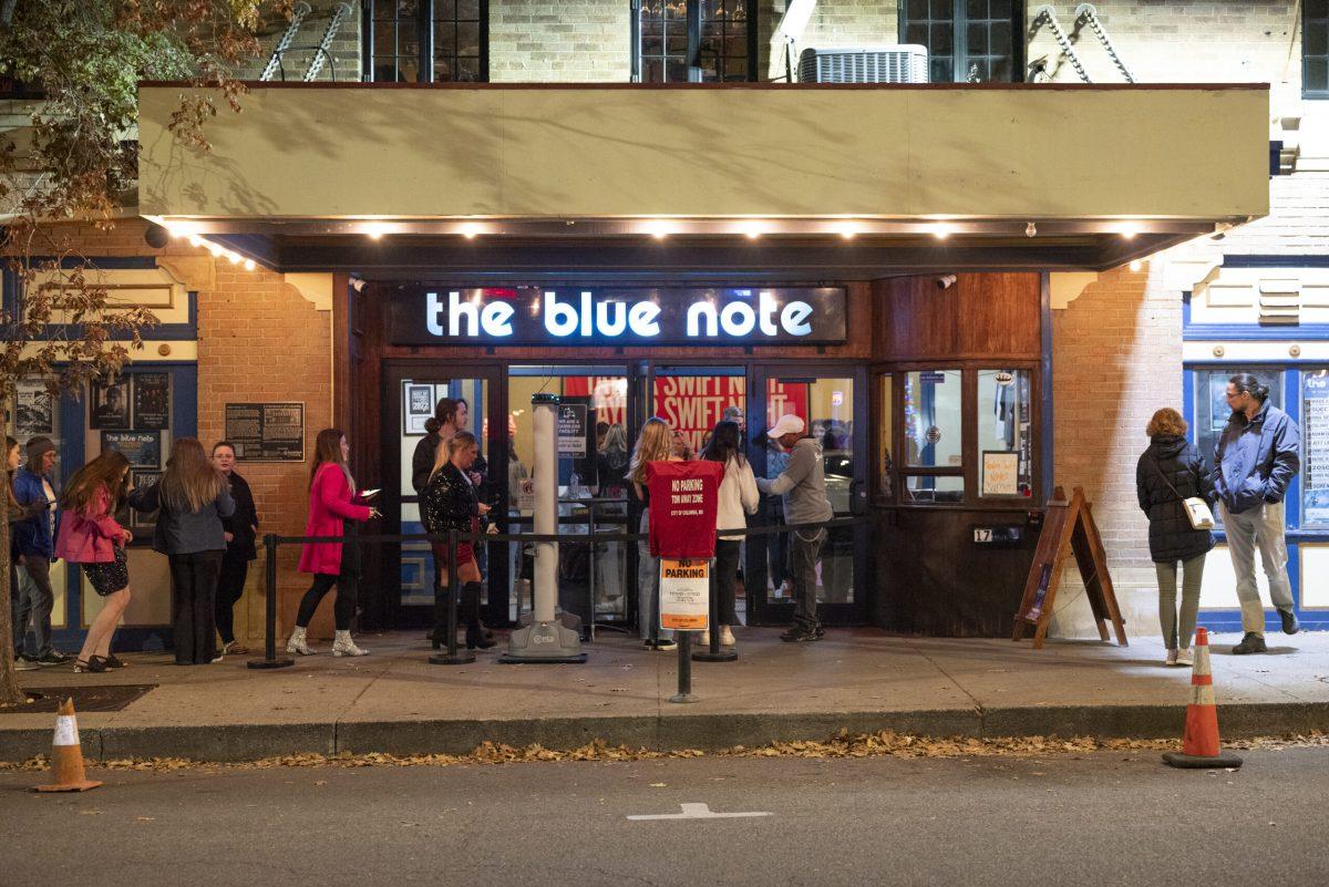 A line of people wait on a sidewalk outside the Blue Note.