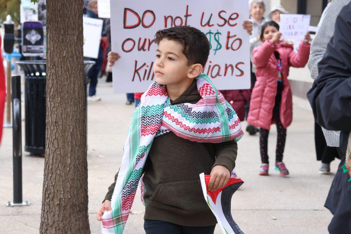 A young child marching through downtown Columbia holding a hand-drawn flag of Palestine.