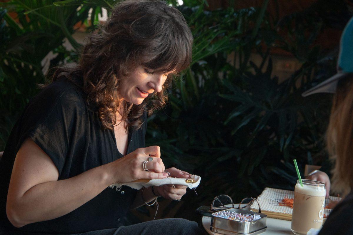 Carly Ryan smiles while embroidering.
