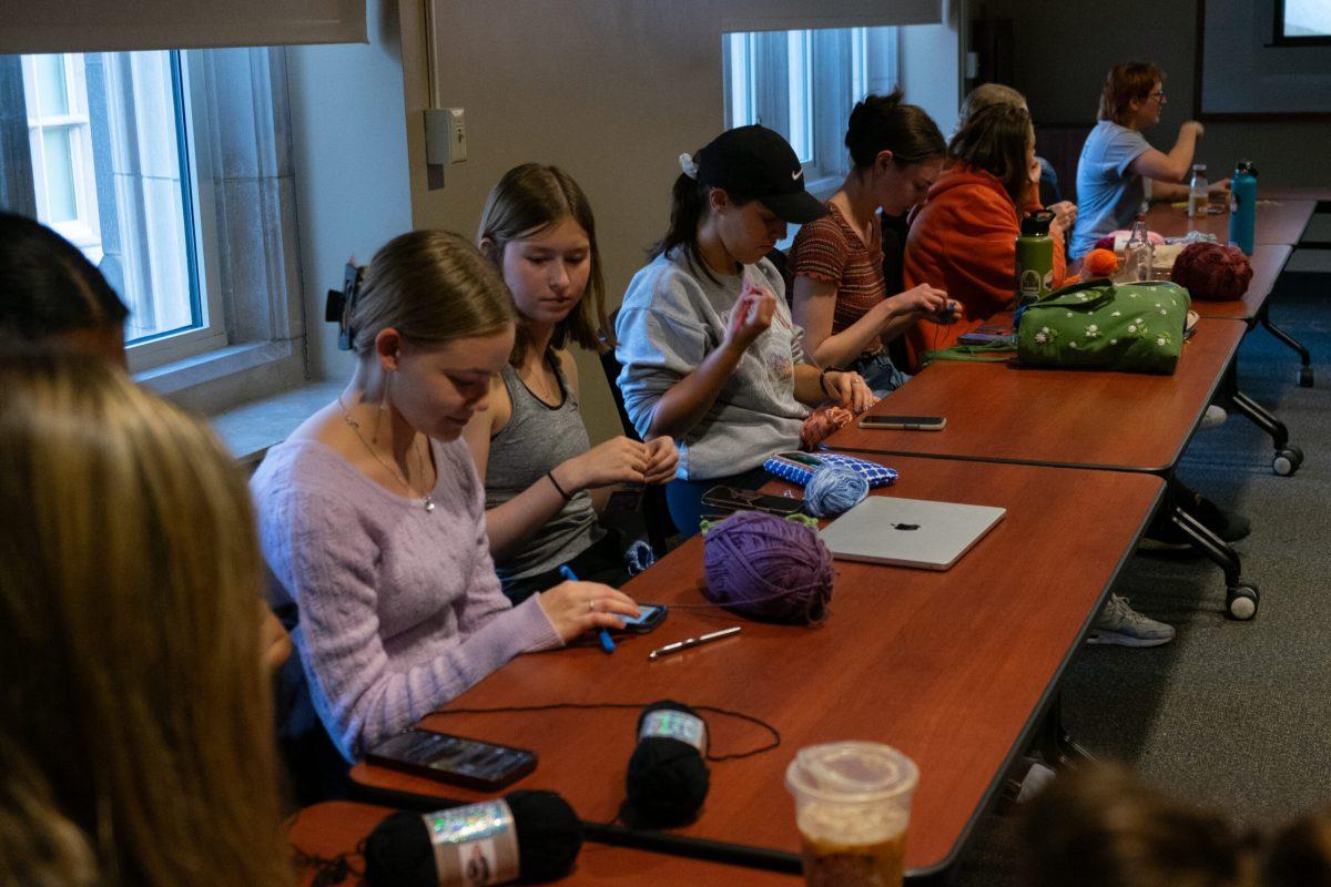 Students sit at tables crocheting.