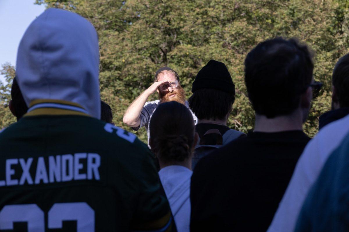 A man wearing a yarmulke shields the sun from his eyes with his hand while looking over a crowd of people. 