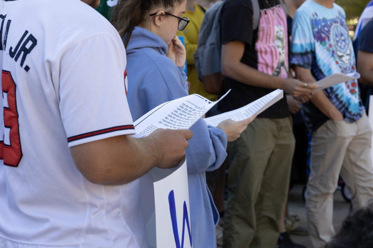 Students look at booklets of prayers written in Yiddish with an English translation.