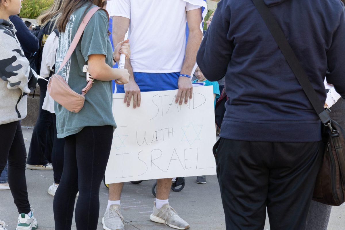 A student holds a poster stating “I Stand With Israel,” surrounded by other students.
