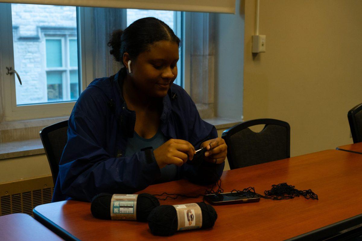 A student crochets at a table.