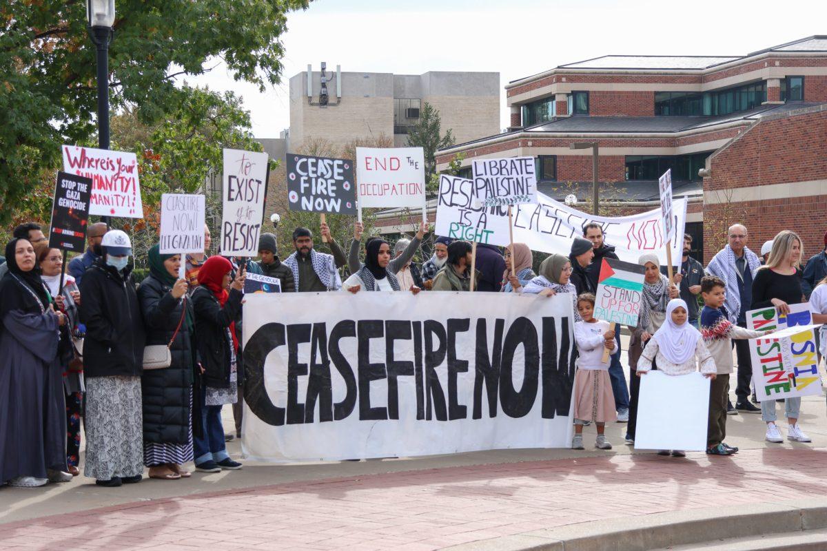 A group of protestors holding signs, many of which call upon officials to advocate for a ceasefire in Gaza.
