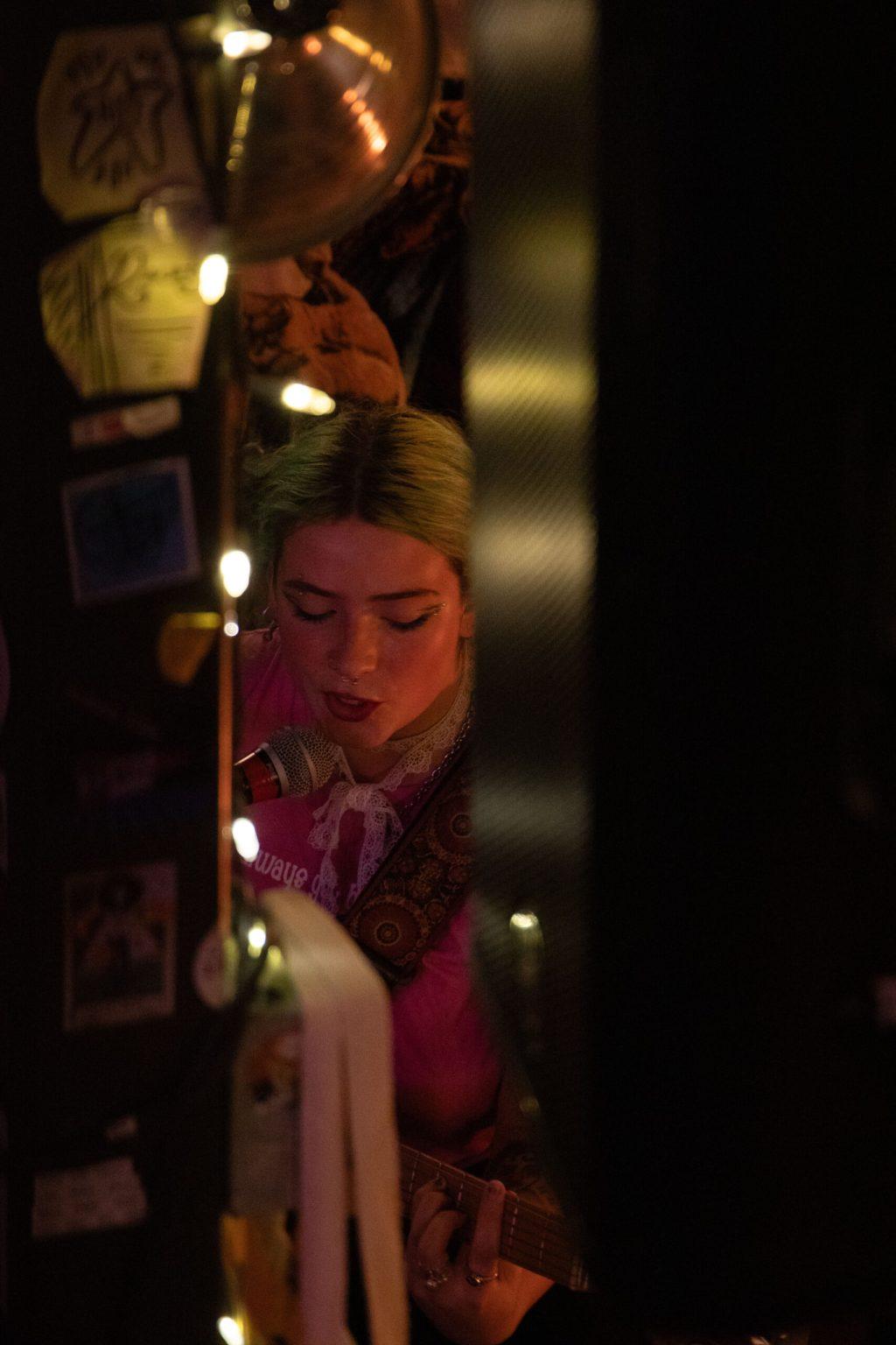 Liv Burney sings into the side of her microphone in between two columns.