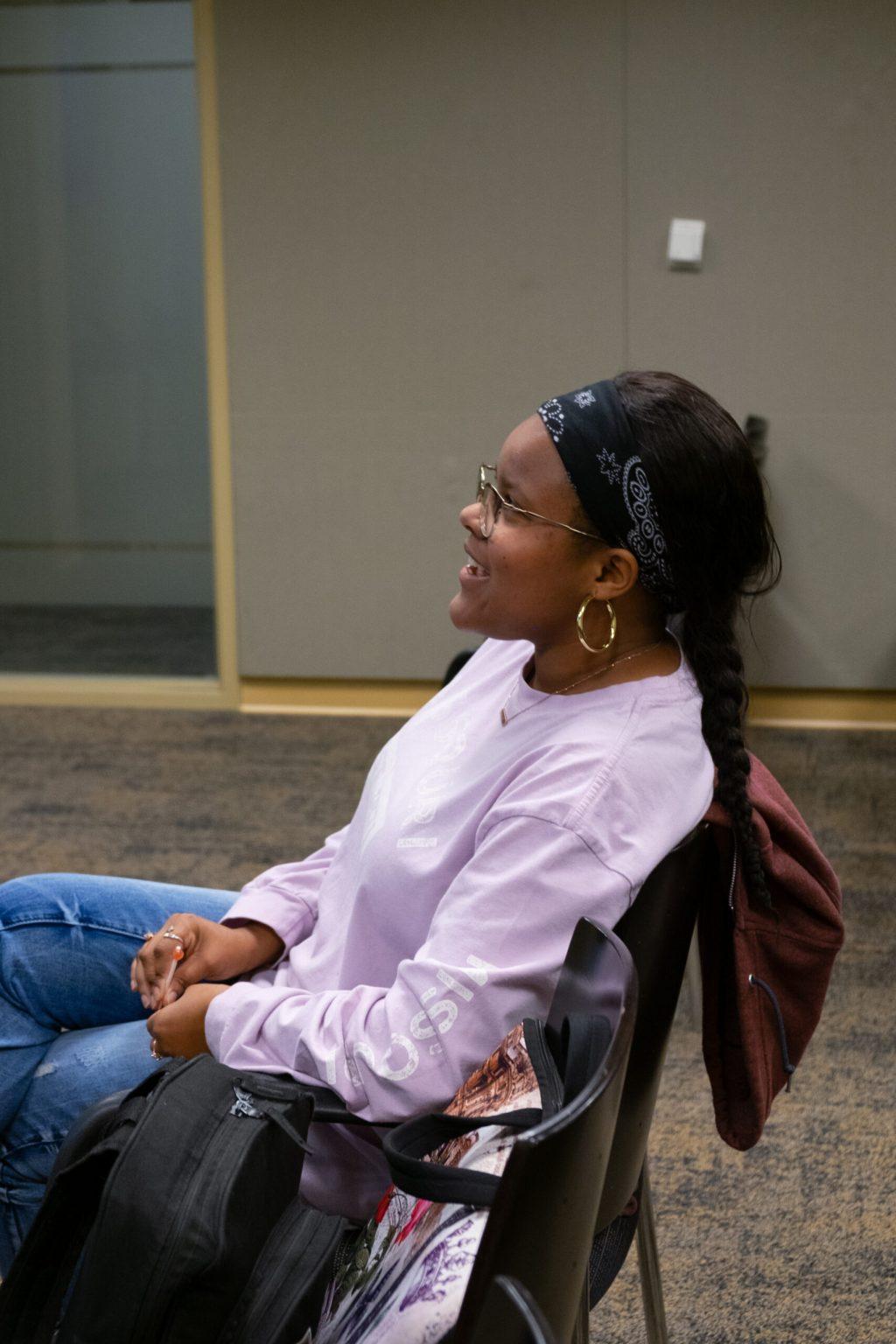 A woman talks while sitting in a chair.
