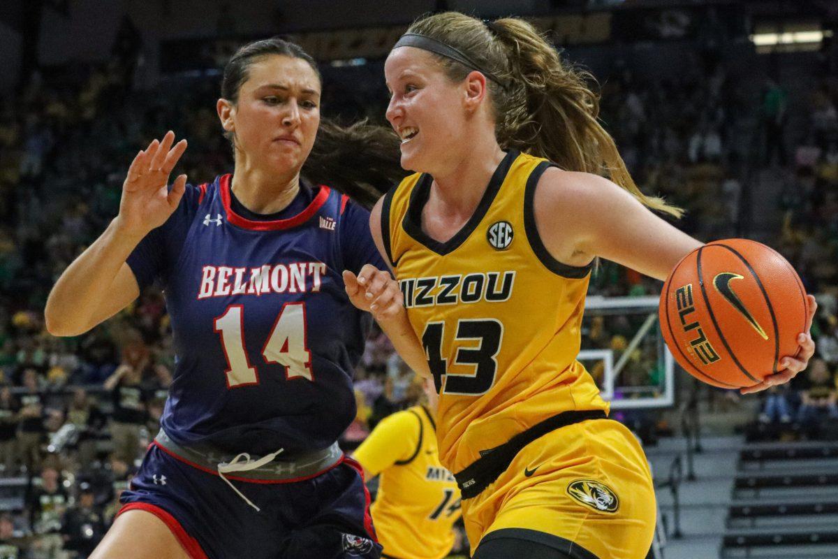 Haley Frank, wearing a yellow jersey and holding a basketball, crosses in front of a player in a purple jersey.