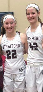 Hayley stands to the right of her twin Kayley. The two are wearing matching white jerseys but are not identical.