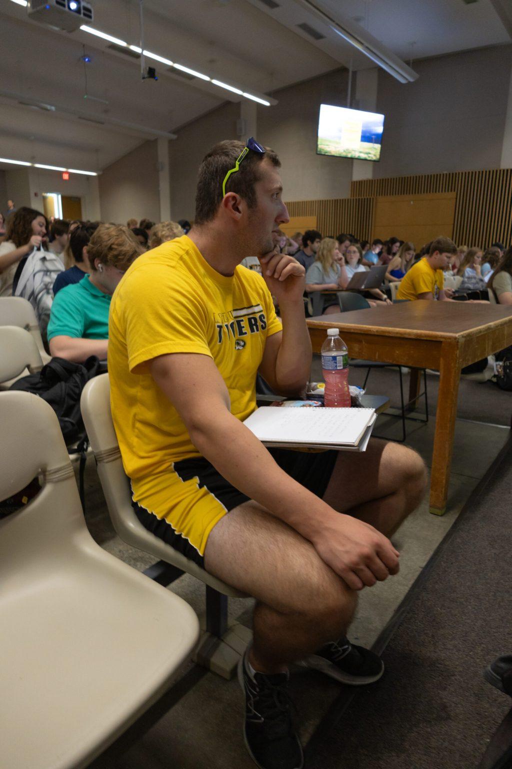 Aidan Dubbert sits in the front row of his class in Conservation Auditorium with his notes.
