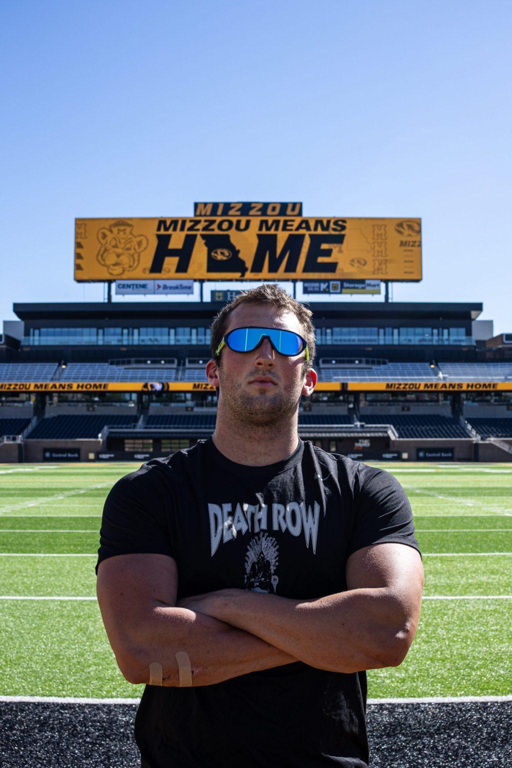 Aidan stands on Faurot Field with the scoreboard behind him with text saying “Mizzou means home.”