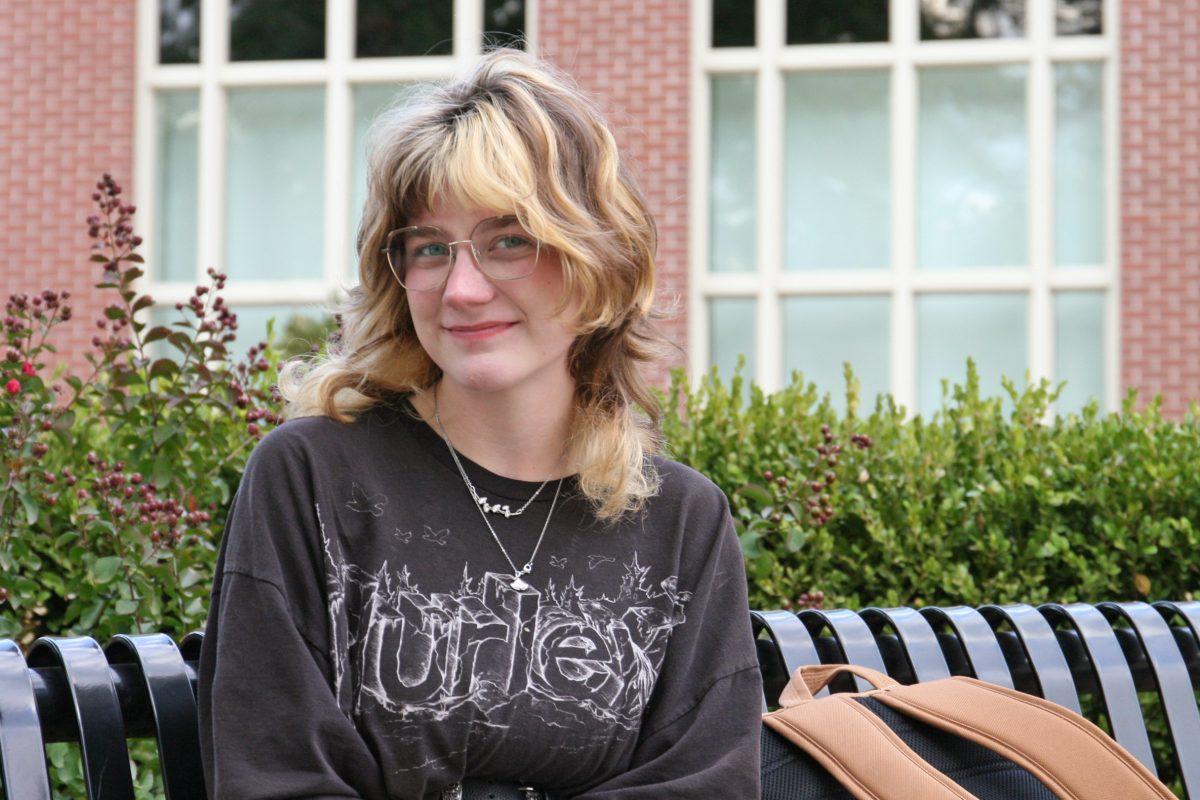 MU student sits on a bench by the Journalism School at MU.
