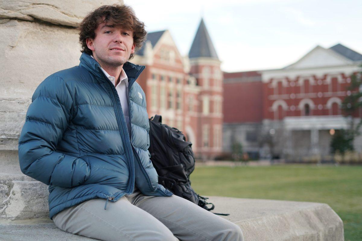 An MU student sits on Columns for a portrait with Jesse Hall in the background.
