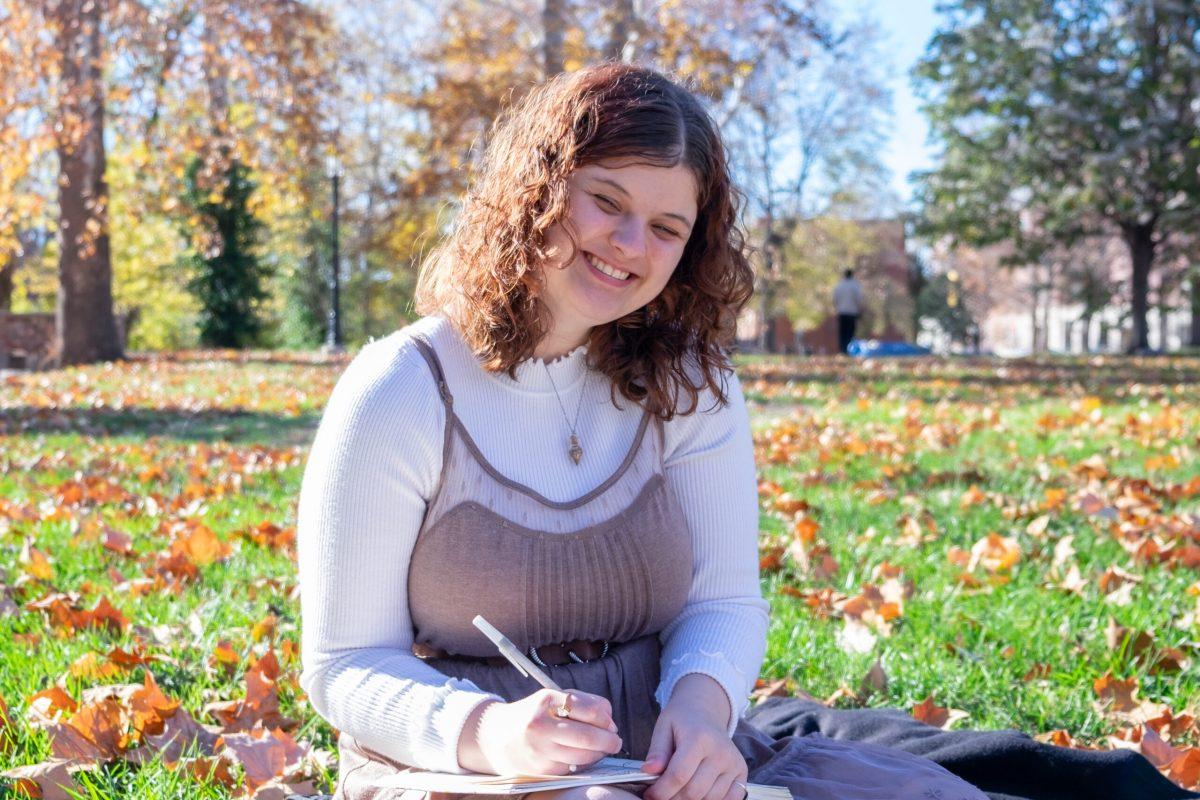 MU student sits on a blanket in the grass.
