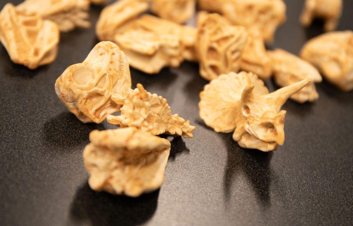 Small, plastic dinosaur fossils sitting on table.