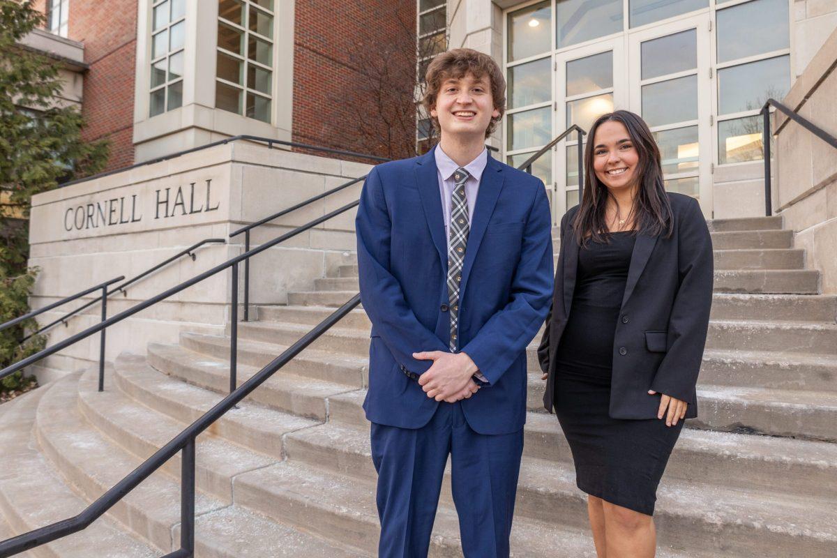 A man and a woman stand together in front of Cornell Hall.